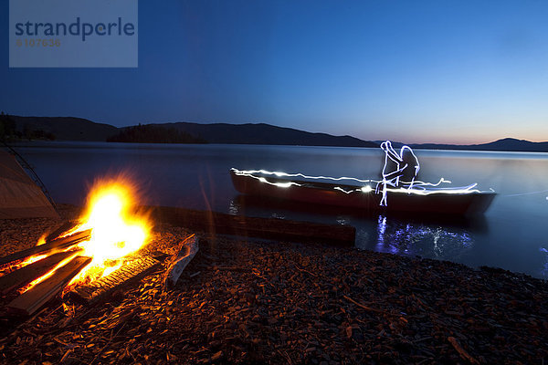 Wasserrand  Mann  Beleuchtung  Licht  Silhouette  See  camping  Feuer  streichen  streicht  streichend  anstreichen  anstreichend  Kanu  Idaho