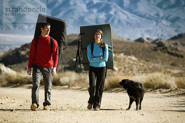 Two climbers  crash pads and dog