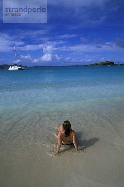 Junge Frau am Strand sitzen.