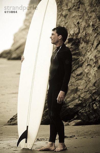 stehend  Strand  Ozean  Steilküste  halten  Surfboard  Wellenreiten  surfen  Hintergrund  Tauchanzug  hinaussehen