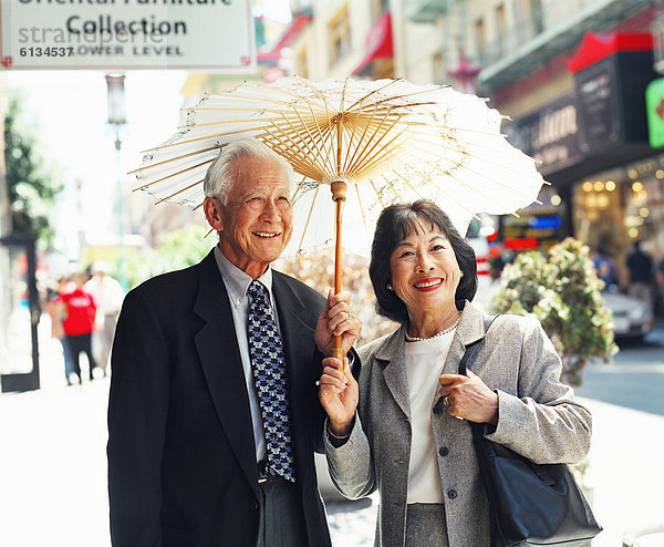 Städtisches Motiv  Städtische Motive  Straßenszene  Straßenszene  Senior  Senioren  Regenschirm  Schirm  Straße  Sonne