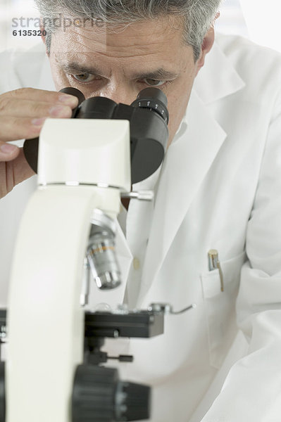 Mann auf der Suche durch Mikroskop