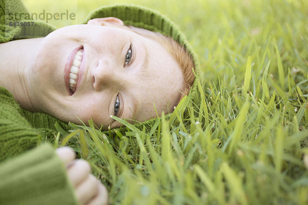 Portrait einer jungen Frau auf Gras liegend