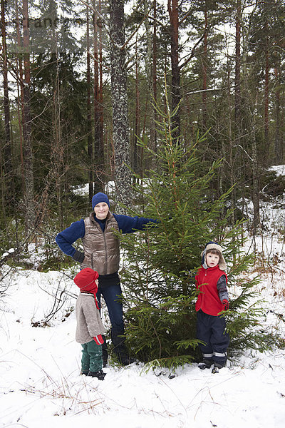 Familie pflückt Weihnachtsbaum im Freien
