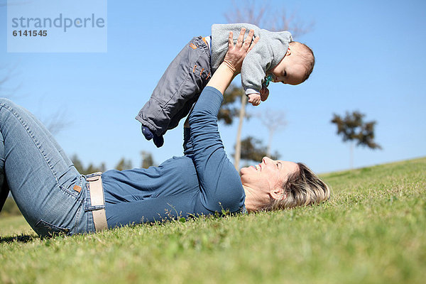 Frau spielt mit Baby im Gras