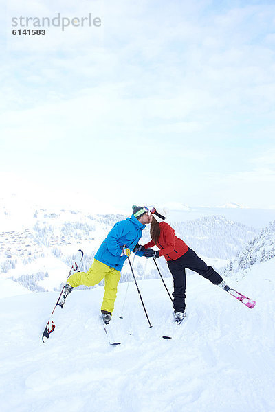 Skifahrer küssen sich auf schneebedecktem Berggipfel