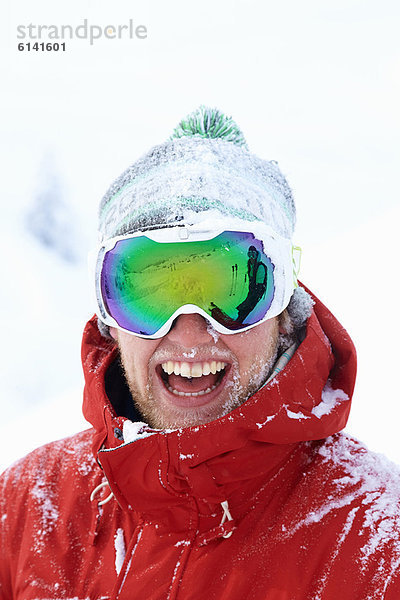 Lächelnder Skifahrer mit Schnee bedeckt