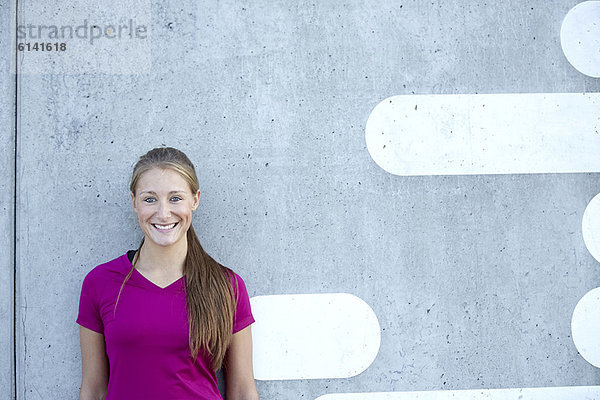 Lächelnde Frau  die sich an die Wand lehnt