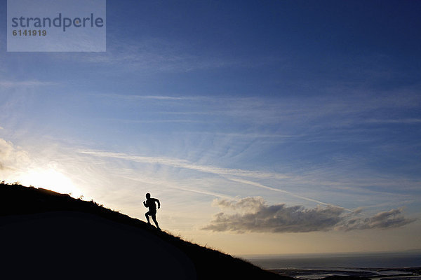 Silhouette eines Wanderers  der den Hang hinaufläuft