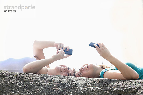 Teenager-Mädchen benutzen Mobiltelefone im Freien