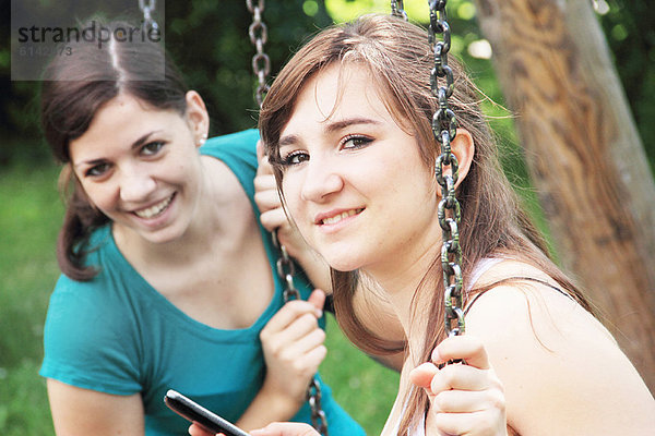 Teenager-Mädchen mit Handy auf Schaukeln