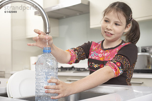 Mädchen beim Füllen der Wasserflasche in der Küche