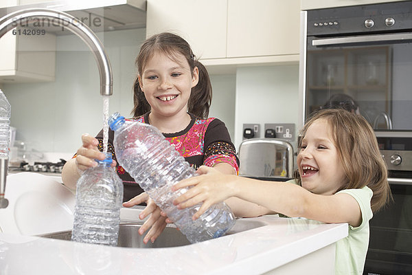 Mädchen beim Füllen der Wasserflasche in der Küche