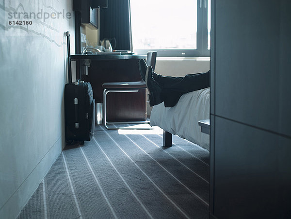 Mann auf Hotelzimmerbett liegend
