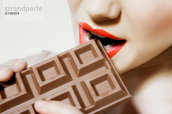 Junge Frau beißt Schokolade  Nahaufnahme  Mund