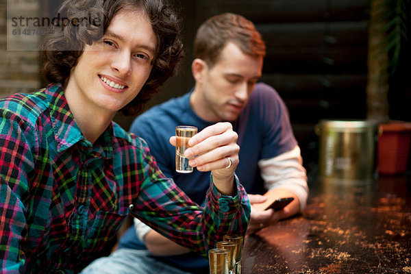 Zwei Männer an der Bar  einer hält ein Schnapsglas