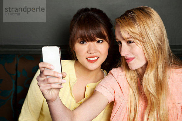 Weibliche Freunde  die sich auf dem Smartphone fotografieren