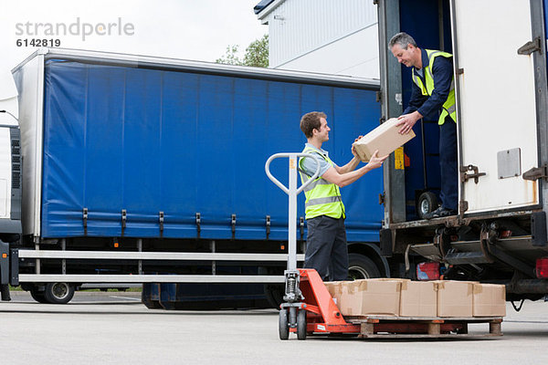 Zwei Männer beim Entladen von Kartons vom LKW