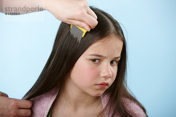 Elternteil kämmt das Haar der Tochter mit Kopfkamm