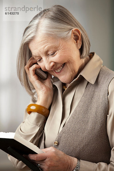 Seniorin mit Bilderrahmen am Telefon