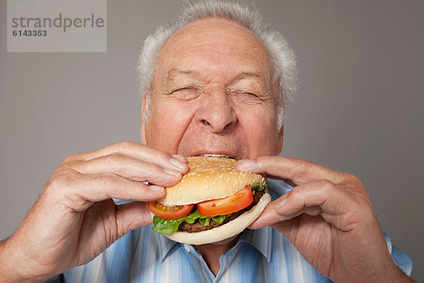 Senior Mann beim Burger essen