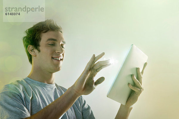Junger Mann mit digitalem Tablett mit Beleuchtung