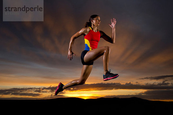Athlet in der Luft gegen Sonnenuntergang