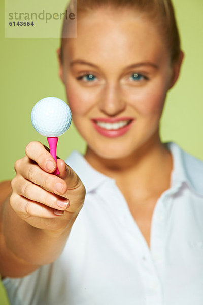 Junge Frau mit Golfball und Tee