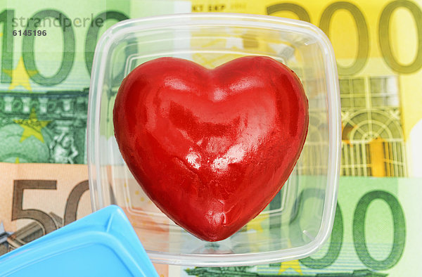 Herz in Frischhaltebox mit Geldscheinen  Symbolbild Organhandel