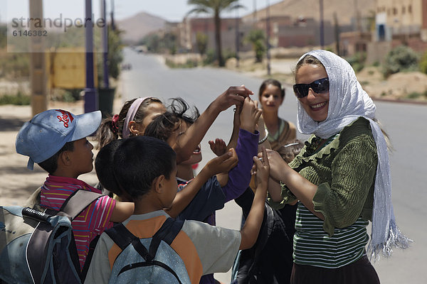 Frau verteilt Bonbons an Schulkinder  Königreich Marokko  Maghreb  Afrika