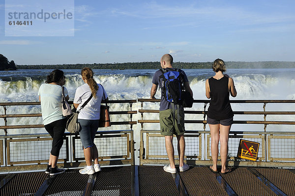 Touristen blicken in den Teufelsschlund  Garganta del Diablo  Wasserfälle von Iguazu oder Iguacu  UNESCO Welterbe  an der Grenze zwischen Brasilien und Argentinien  Landschaft auf der argentinischen Seite  Südamerika