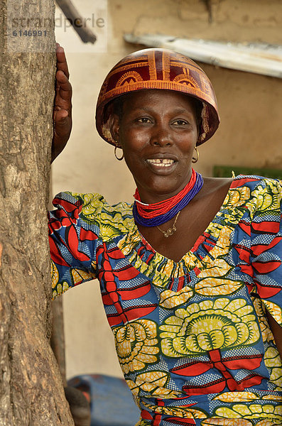 Frau mit dem für die Region typischen Kalebassen-Helm und farbenfrohem Kleid im Dorf Tourou  Kamerun  Zentralafrika  Afrika