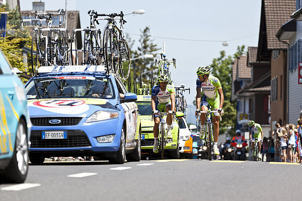 Zwei Radrennfahrer zwischen Mannschafts- und Begleitfahrzeugen bei der Schlussetappe der Tour de Suisse 2012 von Näfels nach Sörenberg  Schweiz  Europa