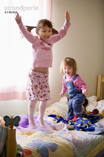 Zwei Mädchen springen auf Bett