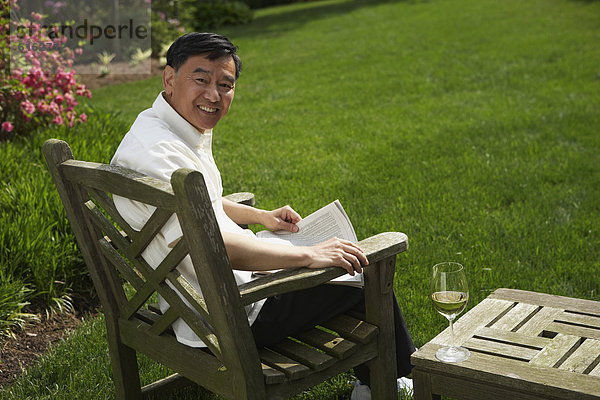 Senior Senioren Mann Garten Hinterhof vorlesen