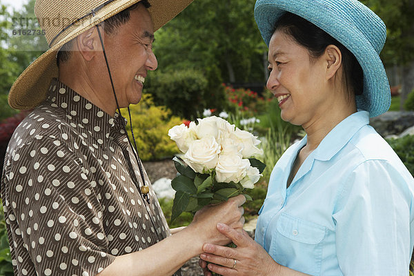 Senior Senioren Mann geben Ehefrau Blume