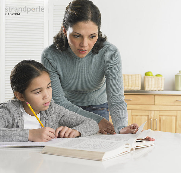 Mutter ihre Tochter bei ihren Hausaufgaben helfen