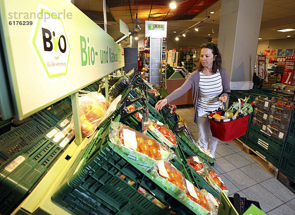 Frau kauft in der Obst- und Gemüseabteilung ein  Bioprodukte  Selbstbedienung  Lebensmittelabteilung  Supermarkt  Deutschland  Europa