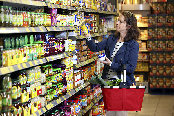 Frau kauft Gemüsekonserven ein  Selbstbedienung  Lebensmittelabteilung  Supermarkt  Deutschland  Europa