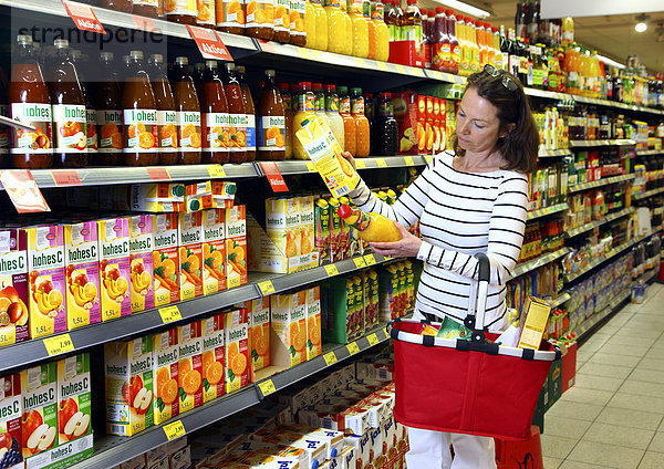 Frau schaut sich die Inhaltsstoffe einer Saftflasche an  Lebensmittelabteilung  Selbstbedienung  Supermarkt  Deutschland  Europa