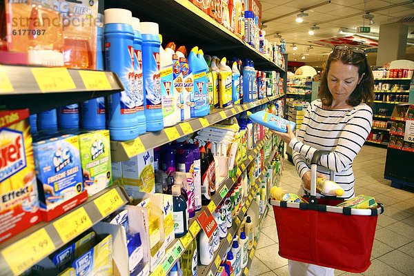 Frau betrachtet Produkte an einem Regal mit Reinigungsmitteln  Haushaltswaren  Selbstbedienung  Supermarkt  Deutschland  Europa
