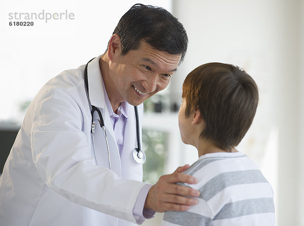 Lächelnder Arzt legt seine Hand auf die Schulter eines Jungen
