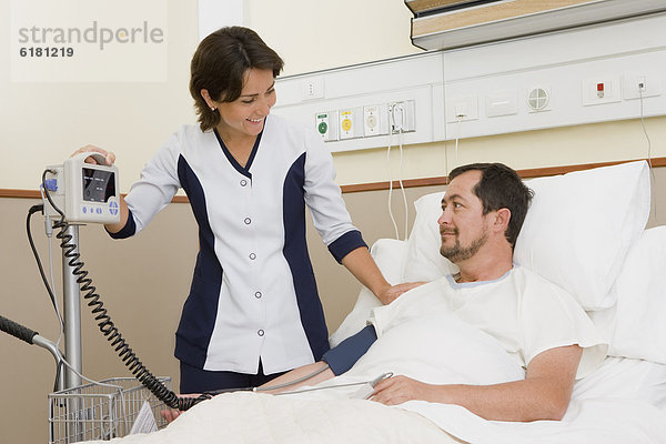 Nurse Taking Patient Blutdruck im Krankenhauszimmer