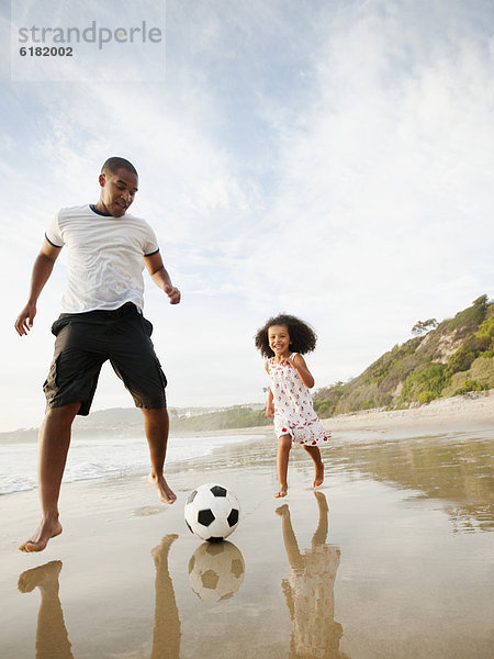 Strand Menschlicher Vater treten schwarz Fußball Tochter Ball Spielzeug