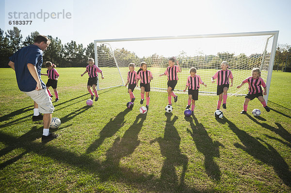 Fußballspieler üben Mädchen