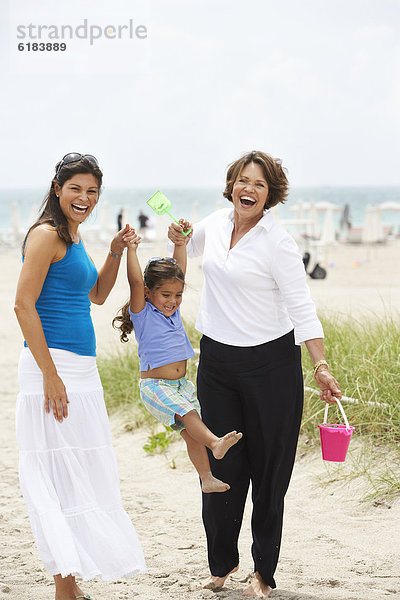 Hispanic grandmother  mother and daughter enjoying beach