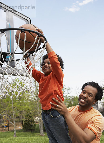 Menschlicher Vater  Sohn  heben  Basketball  einlochen