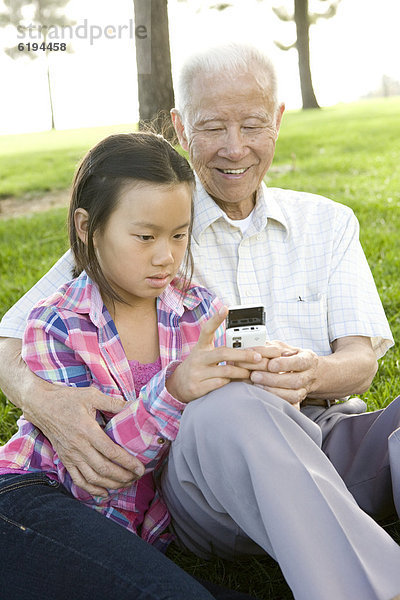 Handy  sitzend  zeigen  chinesisch  Großvater  Gras  Mädchen