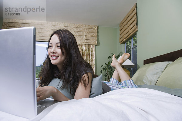 Frau mit Laptop im Bett