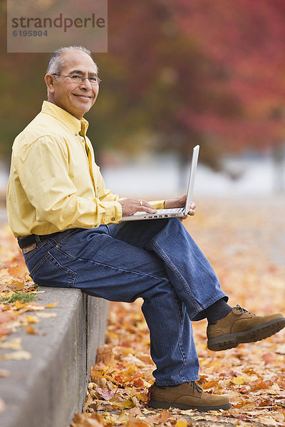 Außenaufnahme  benutzen  Mann  Notebook  Hispanier  Herbst  freie Natur